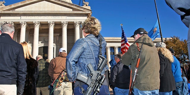 Leslie Nessmith, center, of Edmond, Okla., attends a rally at the state Capitol to mark the start of a new law that allows most adults in Oklahoma to carry a firearm in public without a background check or training. (AP Photo/Sue Ogrocki)