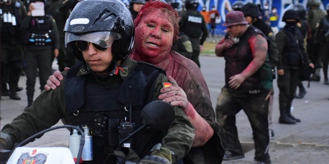 Police rescue Vinto mayor Patricia Arce Guzman on a motorcycle after people threw paint and dirt on her following a fire in Vinto's Town Hall, Quillacollo, Bolivia, November 6, 2019.
