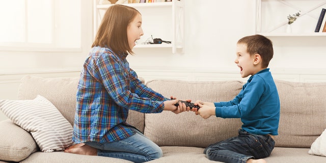 Siblings fighting over remote control at home, brother and sister have quarrel, copy space. (Photo: iStock)