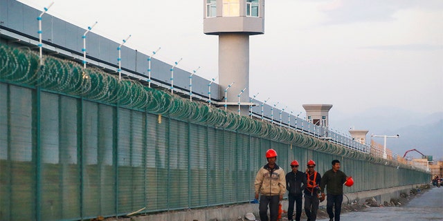 FILE PHOTO: Workers walk by the perimeter fence of what is officially known as a vocational skills education centre in Dabancheng in Xinjiang Uighur Autonomous Region, China September 4, 2018. This centre, situated between regional capital Urumqi and tourist spot Turpan, is among the largest known ones, and was still undergoing extensive construction and expansion at the time the photo was taken. Picture taken September 4, 2018. REUTERS/Thomas Peter/File Photo - RC112C876810