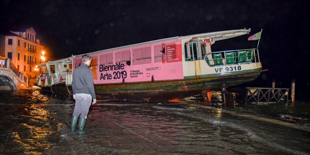 A man looks at a stranded ferry boat, in Venice, Italy, early Wednesday, Nov. 13, 2019.