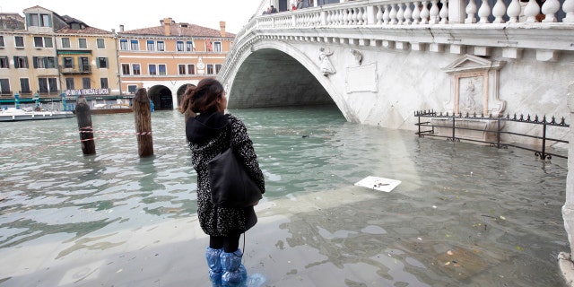 A woman looks at the Rialto Bridge during high water, in Venice, Wednesday, Nov. 13, 2019.