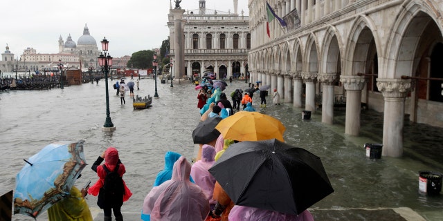 People walk on catwalk set up on the occasion of a high tide, in a flooded Venice, Italy, Tuesday, Nov. 12, 2019.