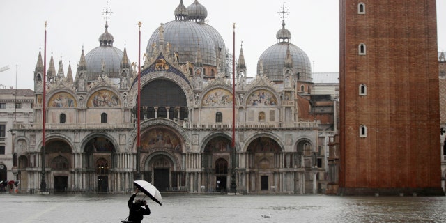 A photographer takes pictures in a flooded St. Mark's Square, in Venice, Italy, Tuesday, Nov. 12, 2019.