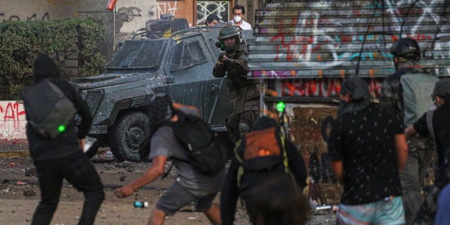 Anti-government demonstrators clash with Chilean police during a protest in Santiago, Chile, Thursday, Nov. 14, 2019. Students in Chile began protesting nearly a month ago over a subway fare hike. The demonstrations have morphed into a massive protest movement demanding improvements in basic services and benefits, including pensions, health, and education. (AP Photo/Esteban Felix)