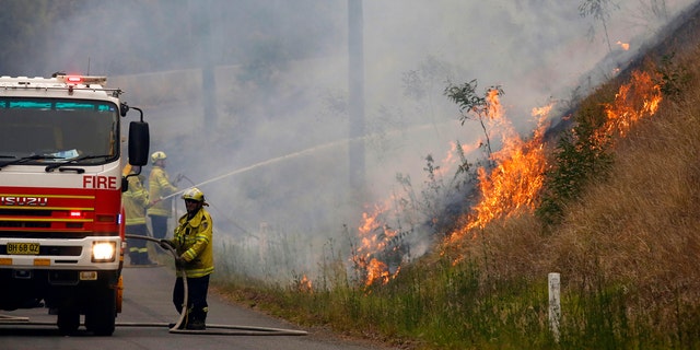 In Monday, Nov. 11, 2019, photo, firefighters work on a controlled burn in Koorainghat, New South Wales state, Australia.