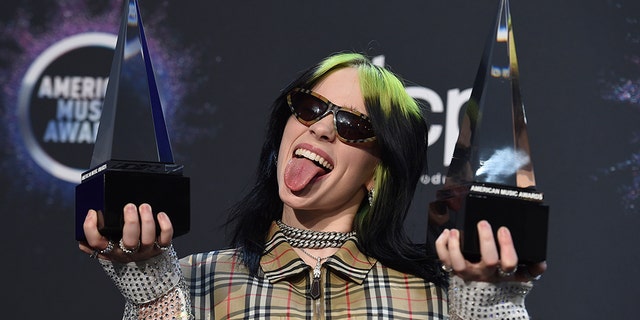 Billie Eilish poses in the press room with the award for new artist of the year and favorite alternative rock artist at the American Music Awards on Sunday, Nov. 24, 2019, at the Microsoft Theater in Los Angeles. (Associated Press)