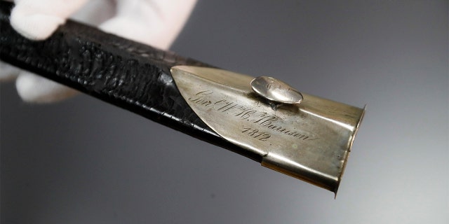 Hamilton County Sheriff Jim Neil points out the engraving 'Gen. W. H. Harrison' on the scabbard of the sword Wednesday. (AP Photo/John Minchillo)