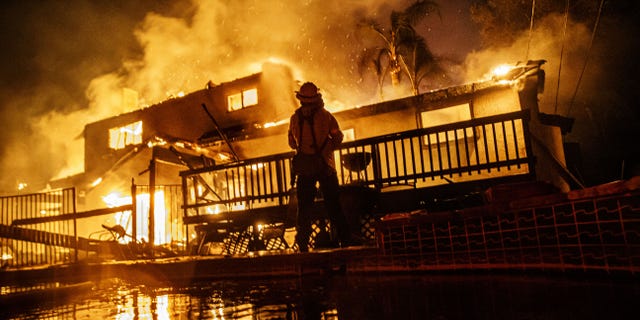 Firefighters work to control the flames as the embers blown by the wind threaten more homes in the North Park neighborhood at the Hillside Fire in San Bernardino on Thursday. (Photo by Marcus Yam/Los Angeles Times via Getty Images)