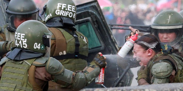 A riot police officer that was on fire is assisted by colleagues during a protest against Chile's government in Santiago, Chile, Nov. 4.