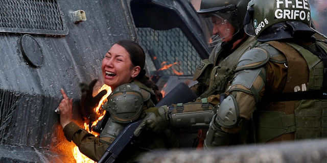 A riot police officer on fire reacts during a protest against Chile's government in Santiago, Chile