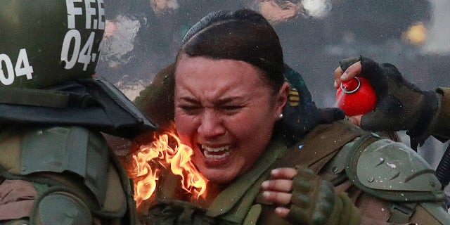 A riot police officer on fire is assisted by colleagues during a protest against Chile's government in Santiago, Chile, Nov. 4, 2019. 