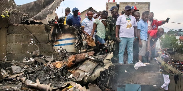 Rescuers and onlookers gather amidst the debris of an aircraft that crashed in Goma, Congo on Sunday. (AP Photo/Justin Kabumba)