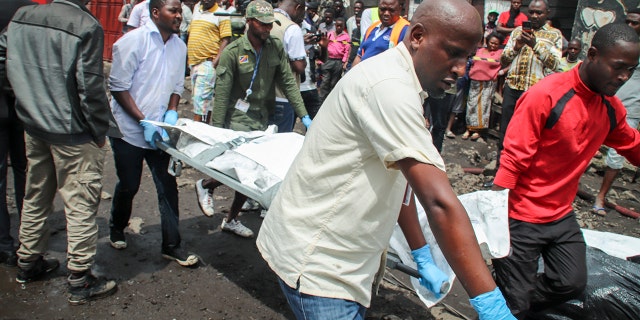Rescuers remove bodies from the debris of an aircraft that crashed into two residential homes. (AP Photo/Justin Kabumba)