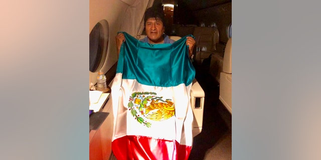 Morales held a Mexican flag aboard a Mexican Air Force aircraft on Monday after having been granted asylum in Mexico following his resignation. (Mexico's Foreign Minister via AP)
