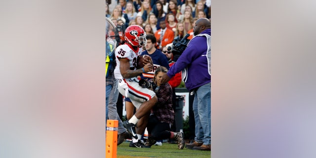 Georgia running back Brian Herrien (35) runs out of bounds and into a photographer during the first half of an NCAA college football game against Auburn, Saturday, Nov. 16, 2019, in Auburn, Ala. (AP Photo/Butch Dill)