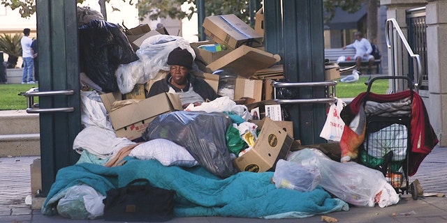 A homeless woman sits at a bus stop in Oakland, surrounded by her belongings. (Credit: Gabe Nazario/Fox News)