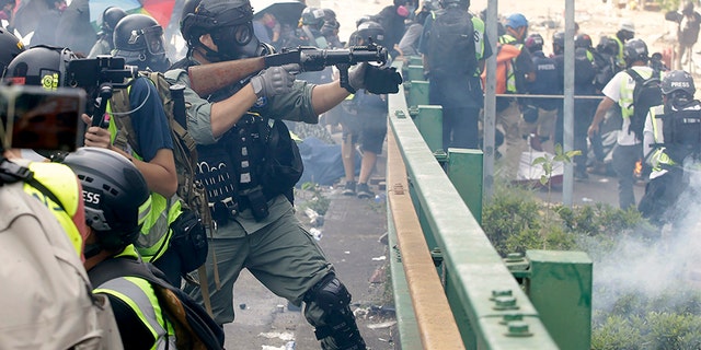 A police officer prepares to fire tear gas canisters during a clash with protesters near Hong Kong Polytechnic University on Nov. 18.