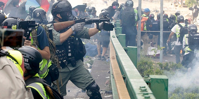 A police officer prepares to fire tear gas canisters during a clash with protesters near the Hong Kong Polytechnic University in Hong Kong on Monday.