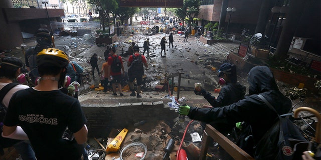 Protesters stand on the steps of the Hong Kong Polytechnic University on Monday. Police there have swooped in with tear gas and batons as protesters who have taken over the university campus are making an apparent last-ditch effort to escape arrest. (AP)