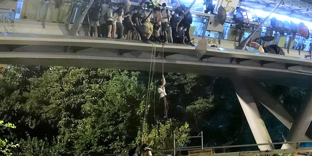 Protestors use a rope to lower themselves from a pedestrian bridge to waiting motorbikes in order to escape from Hong Kong Polytechnic University late Monday. (AP)