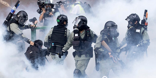 Police in riot gear move through a cloud of smoke as they detain a protester at the Hong Kong Polytechnic University on Nov. 18.