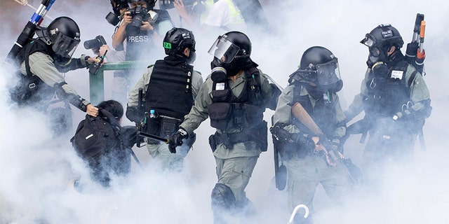 Police in riot gear move through a cloud of smoke as they detain a protester at the Hong Kong Polytechnic University in Hong Kong, on Monday.