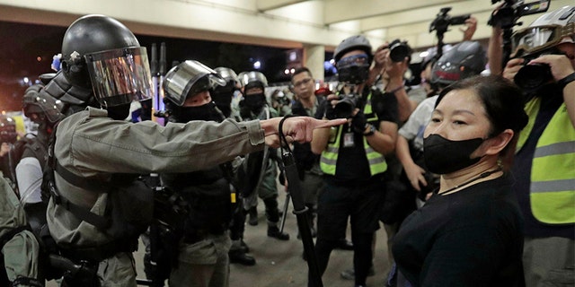 Police in riot gear ask a woman to take off her mask outside a train station in Hong Kong, on Nov. 3. (AP)