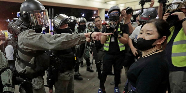 Police in riot gear ask a woman to take off her mask outside a train station in Hong Kong, on Nov. 3. (AP)