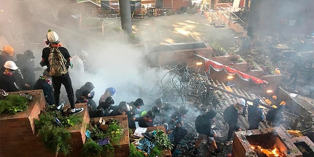 Protesters go down the steps at the front entrance of Hong Kong Polytechnic University in Hong Kong in an attempt to flee Monday.