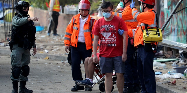 A police officer gestures to medics helping protesters leave the grounds of the Polytechnic University in Hong Kong on Wednesday. (AP)