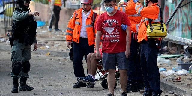 A police officer gestures to medics helping protesters leave the grounds of the Polytechnic University in Hong Kong on Wednesday. (AP)