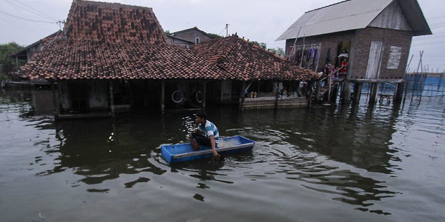 DEMAK, INDONESIA FEBRUARY 2: A man uses a handmade boat to reach his water-logged home in Sriwulan village, Sayung sub-district of Demak regency, Central Java, Indonesia on February 2, 2018.