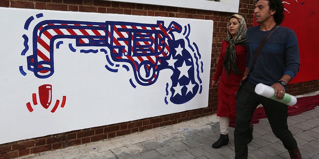 Iranians walk past a new mural painted on the walls of the former US embassy in the capital Tehran on November 2, 2019. (Photo by ATTA KENARE / AFP) (Photo by ATTA KENARE/AFP via Getty Images)