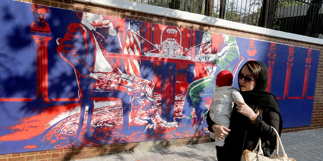 An Iranian woman holding a baby walks past a new mural painted on the walls of the former US embassy in the capital Tehran on November 2, 2019. (Photo by ATTA KENARE / AFP) (Photo by ATTA KENARE/AFP via Getty Images)