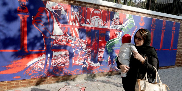 An Iranian woman holding a baby walks past a new mural painted on the walls of the former US embassy in the capital Tehran on November 2, 2019. (Photo by ATTA KENARE / AFP) (Photo by ATTA KENARE/AFP via Getty Images)