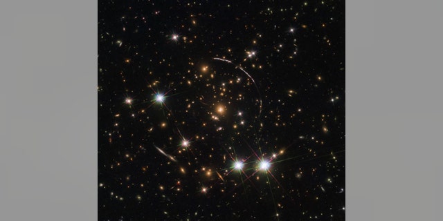 The Hubble Space Telescope recently captured 12 mirror images of the distant, gravitationally-lensed Sunburst Arc. The galaxy can be seen here in this "kaleidoscope" image distributed across four arcs (the elongated lines). (Credit: NASA, ESA and E. Rivera-Thorsen (Institute of Theoretical Astrophysics Oslo, Norway))