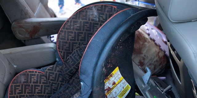 A security baby car seat stained in blood is pictured in a bullet-riddled vehicle belonging to one of the families. 