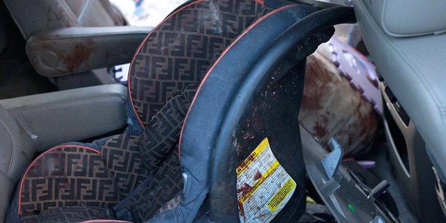 A security baby car seat stained in blood is pictured in a bullet-riddled vehicle belonging to one of the families. 