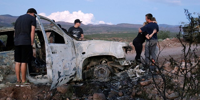 Relatives of the innocent victims observe the wreckage of a burn-out car where several members of a family were found shot and burned to death. November 5, 2019. 