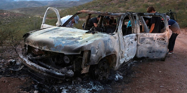 Members of the Lebaron family watch the burned car where part of the nine murdered members of the family were killed during a suspected cartel ambush in the Sonora mountains in Mexico.