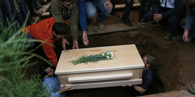 The coffin containing the remains of 12-year-old Howard Jacob Miller Jr. was lowered into a grave on Friday. [Associated Press)