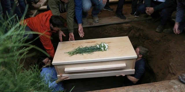 The coffin containing the remains of 12-year-old Howard Jacob Miller Jr. was lowered into a grave on Friday. [Associated Press)