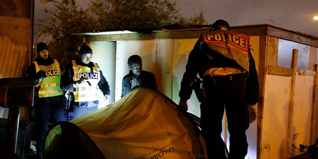 Police officers evacuate a migrant from a camp on Thursday in Paris. (AP)