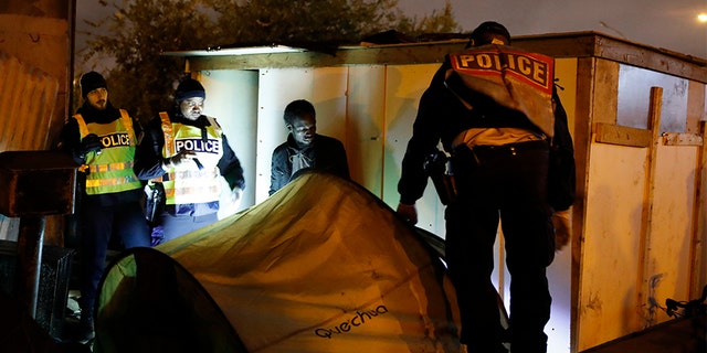 Police officers evacuate a migrant from a camp on Thursday in Paris. (AP)
