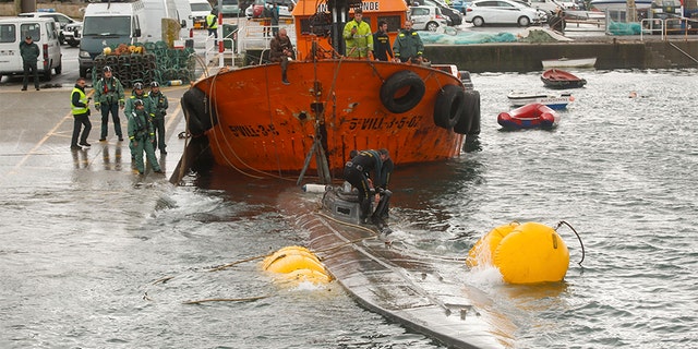Spanish civil guard tow a sunken submarine believed to be carrying tons of cocaine in Aldan harbor, northwest Spain, on Tuesday. (AP/Europa Press)