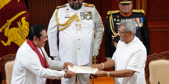 Sri Lanka's President Gotabaya Rajapaksa, right, accepts official documents from his brother Mahinda Rajapaksa after appointing him as prime minister at the presidential secretariat in Colombo, Sri Lanka, on Thursday. (AP)