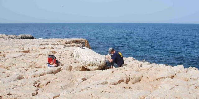 Klaus Reicherter from the University of Aachen examines a boulder that the tsunami carried onto the cliffs. (Gösta Hoffmann/Uni Bonn)