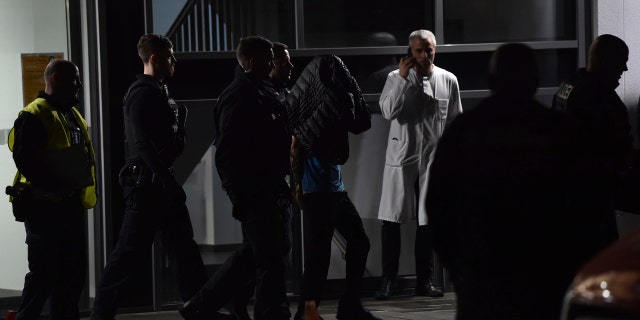 A man is arrested by the police at a hospital in Berlin, Germany after the son of former German Richard von Weizsaecker president was killed while he was giving a lecture. (Paul Zinken/dpa via AP)
