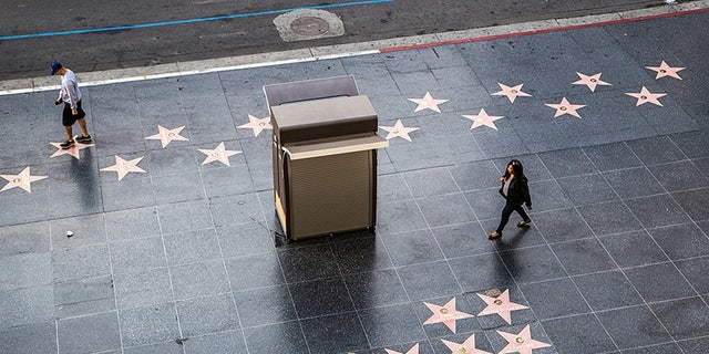 FILE- Les gens qui marchent le long du Hollywood Walk of Fame lors d'une journée ensoleillée à Los Angeles.  Il y a plus de 2000 tuiles sur le Walk of Fame pour honorer les stars.
